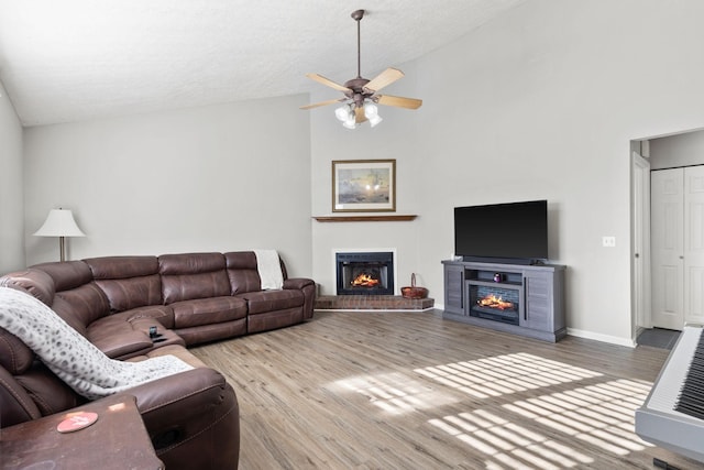 living room with ceiling fan, hardwood / wood-style floors, and vaulted ceiling