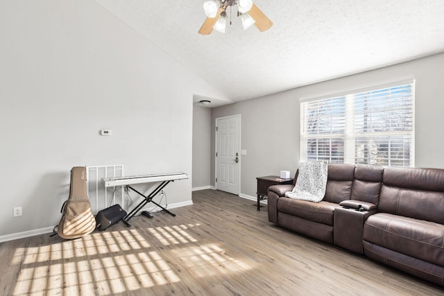 living room featuring ceiling fan, light hardwood / wood-style floors, a textured ceiling, and vaulted ceiling