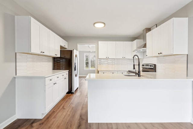 kitchen featuring white cabinets, wall chimney range hood, and kitchen peninsula