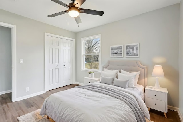 bedroom featuring ceiling fan, a closet, wood finished floors, and baseboards