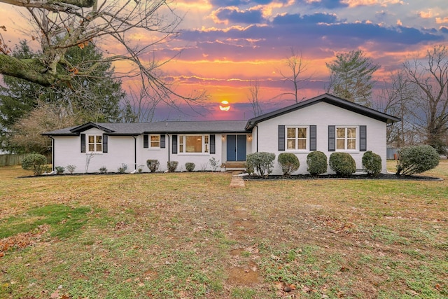 ranch-style home featuring brick siding and a lawn