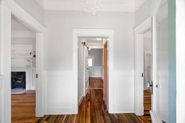 hall with dark hardwood / wood-style flooring, crown molding, and a notable chandelier