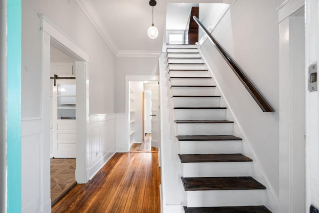 stairway with hardwood / wood-style floors and ornamental molding