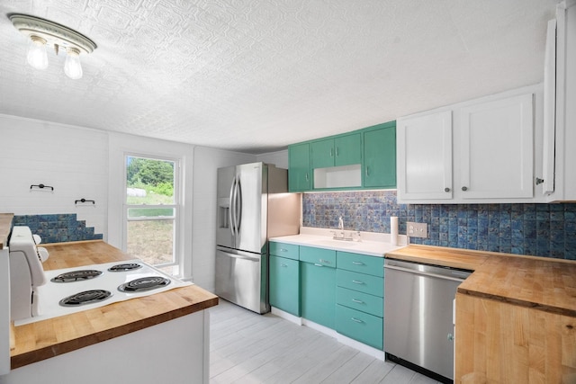 kitchen featuring white cabinets, sink, decorative backsplash, butcher block counters, and stainless steel appliances