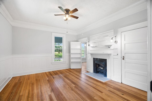 unfurnished living room with hardwood / wood-style floors, ceiling fan, ornamental molding, and a textured ceiling