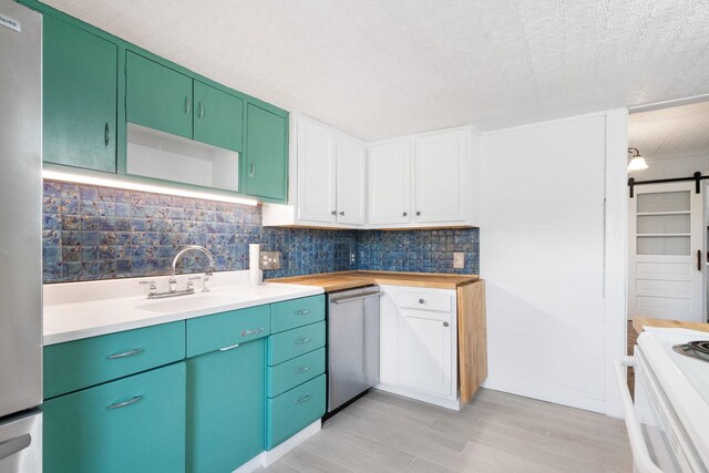 kitchen with a barn door, tasteful backsplash, stainless steel dishwasher, and sink