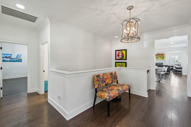 sitting room with crown molding, dark wood-type flooring, and an inviting chandelier