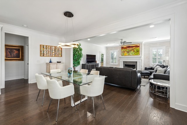 dining space featuring a fireplace, a healthy amount of sunlight, crown molding, and dark wood-type flooring