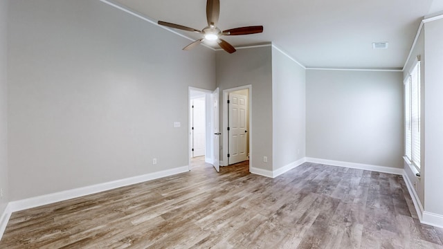 empty room with a wealth of natural light, ceiling fan, light wood-type flooring, and ornamental molding