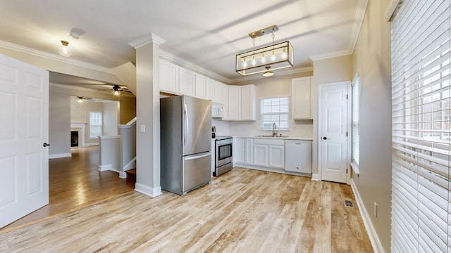 kitchen with sink, stainless steel appliances, pendant lighting, white cabinets, and light wood-type flooring