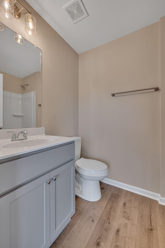 bathroom featuring a shower, hardwood / wood-style floors, vanity, and toilet