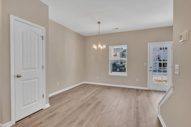 unfurnished room with a chandelier and light wood-type flooring