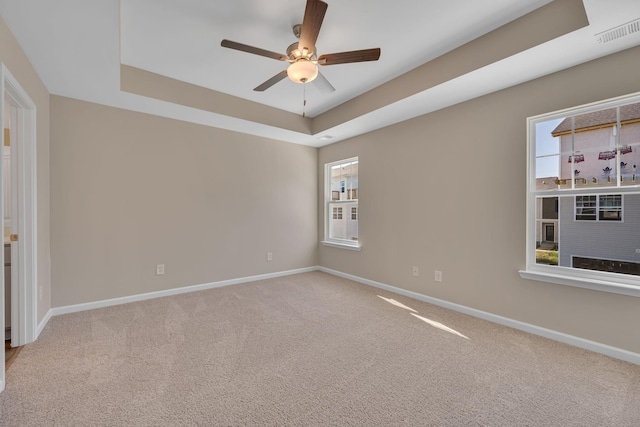 carpeted empty room with a raised ceiling and ceiling fan