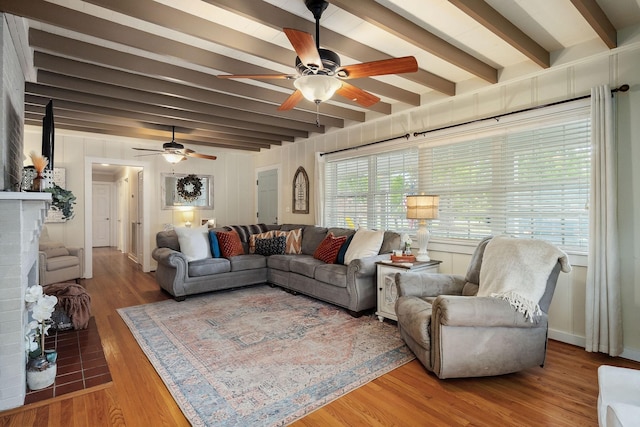 living room with ceiling fan, beam ceiling, and wood-type flooring