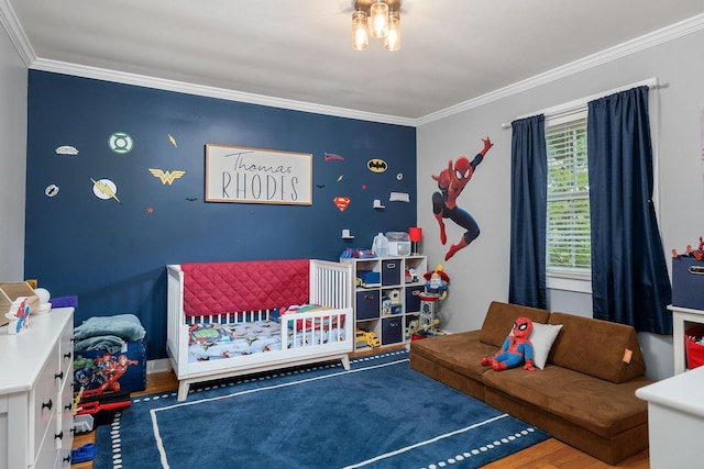 bedroom with a crib, wood-type flooring, and crown molding