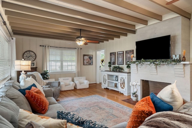 living room with beamed ceiling, ceiling fan, a fireplace, and hardwood / wood-style flooring