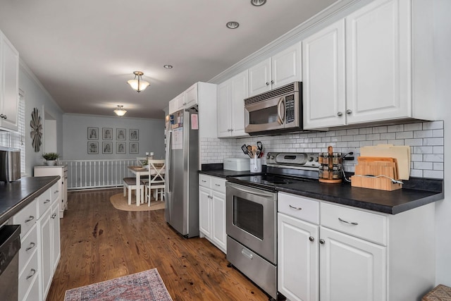 kitchen featuring tasteful backsplash, white cabinets, dark wood-type flooring, and appliances with stainless steel finishes