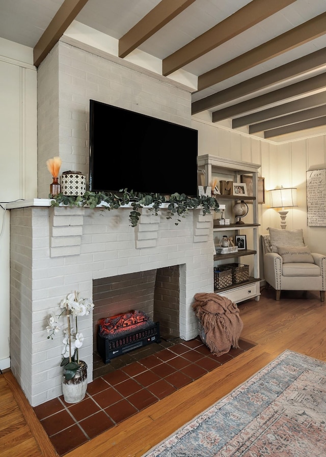 living room with beamed ceiling, dark wood-type flooring, and a brick fireplace