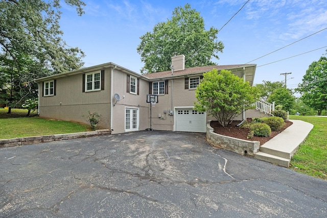 view of front of home featuring a front lawn, a garage, and french doors