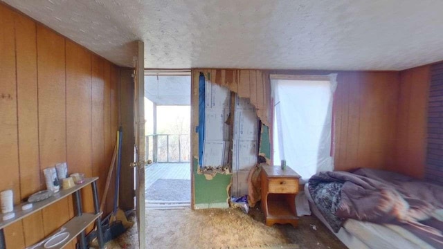 carpeted bedroom with wood walls and a textured ceiling