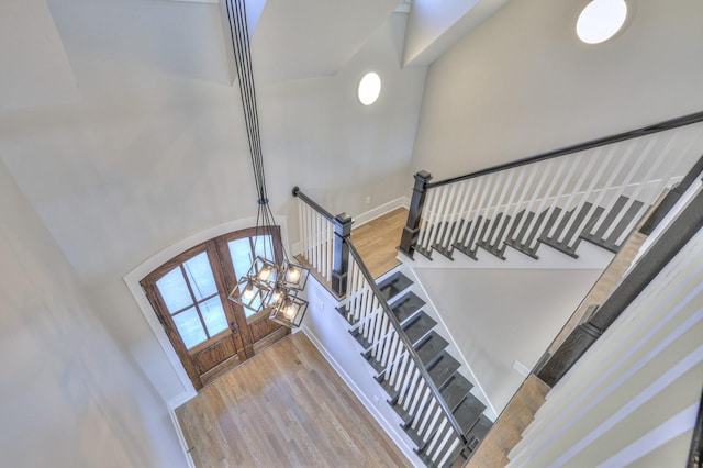 stairway featuring hardwood / wood-style flooring, a towering ceiling, and a notable chandelier