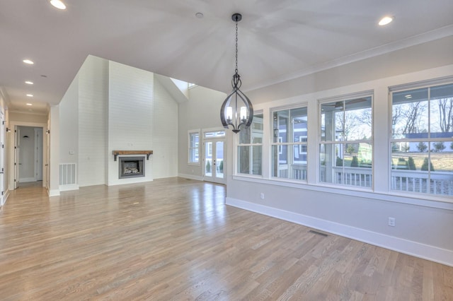 unfurnished living room featuring a notable chandelier, light wood-type flooring, a fireplace, and ornamental molding