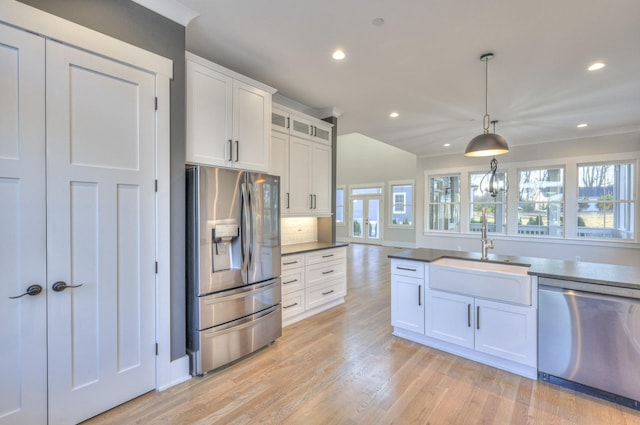 kitchen featuring sink, a healthy amount of sunlight, stainless steel appliances, pendant lighting, and white cabinets