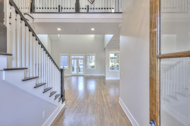 foyer entrance featuring french doors, light hardwood / wood-style floors, and a high ceiling