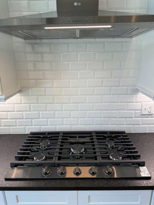 interior details with stainless steel gas stovetop, white cabinetry, range hood, and tasteful backsplash