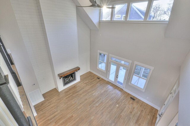 unfurnished living room with light hardwood / wood-style flooring and a towering ceiling