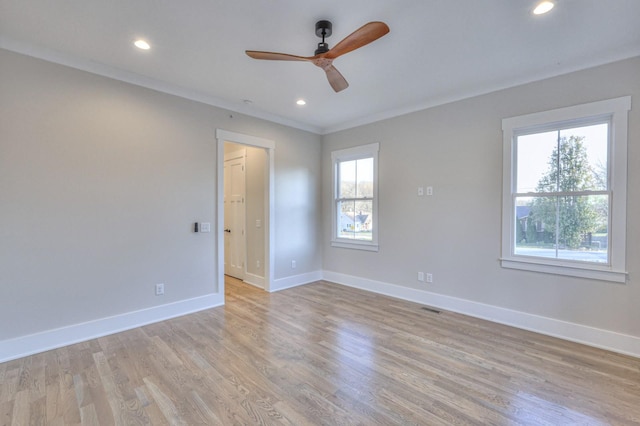 empty room with plenty of natural light, light hardwood / wood-style floors, ornamental molding, and ceiling fan