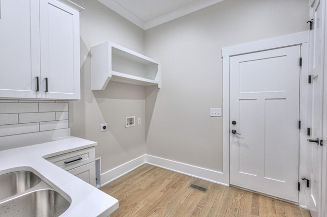 washroom with cabinets, hookup for an electric dryer, crown molding, hookup for a washing machine, and light wood-type flooring