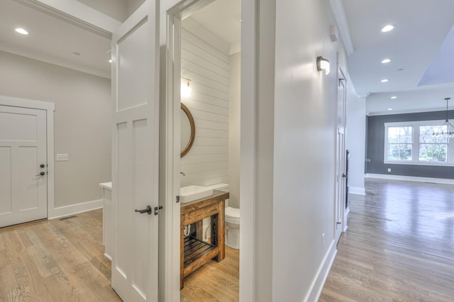 hall with light wood-type flooring and ornamental molding