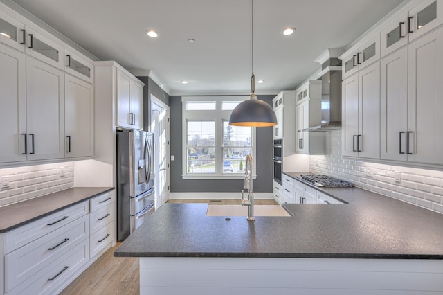 kitchen featuring sink, stainless steel appliances, wall chimney range hood, pendant lighting, and decorative backsplash