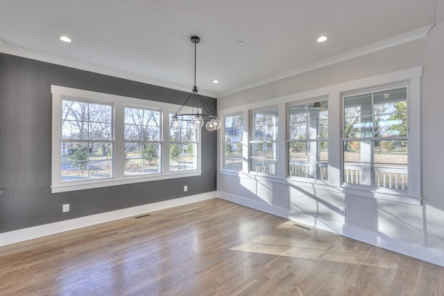 unfurnished dining area with crown molding, hardwood / wood-style floors, a healthy amount of sunlight, and ceiling fan with notable chandelier