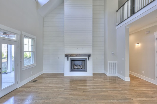 unfurnished living room featuring a high ceiling and light hardwood / wood-style flooring