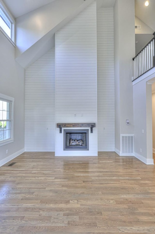 unfurnished living room with light hardwood / wood-style floors and high vaulted ceiling