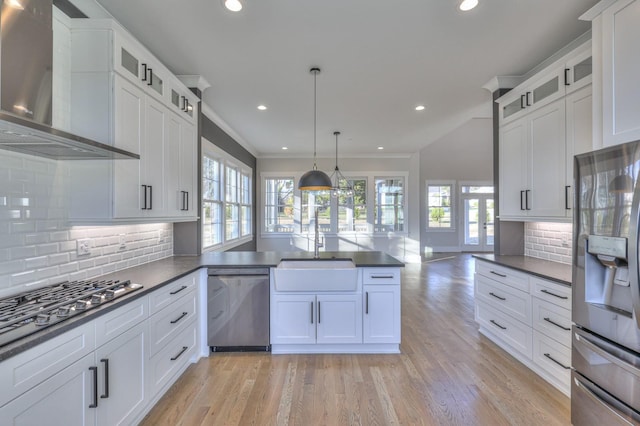 kitchen with backsplash, wall chimney range hood, sink, hanging light fixtures, and appliances with stainless steel finishes