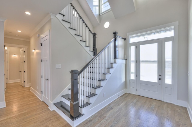 entrance foyer featuring crown molding and light hardwood / wood-style floors