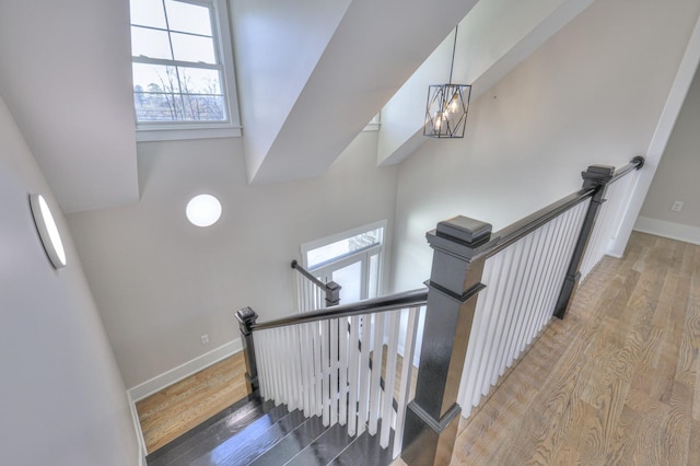 stairway with wood-type flooring and an inviting chandelier