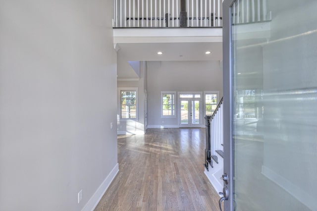 hall with wood-type flooring, a high ceiling, and french doors