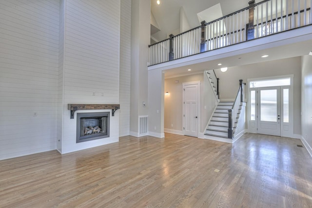 unfurnished living room with a towering ceiling and light hardwood / wood-style floors