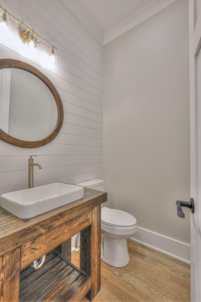 bathroom featuring wood-type flooring, vanity, toilet, and ornamental molding