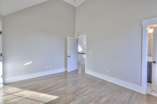 empty room featuring light wood-type flooring and high vaulted ceiling