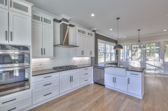 kitchen with white cabinets, appliances with stainless steel finishes, decorative light fixtures, and light hardwood / wood-style floors