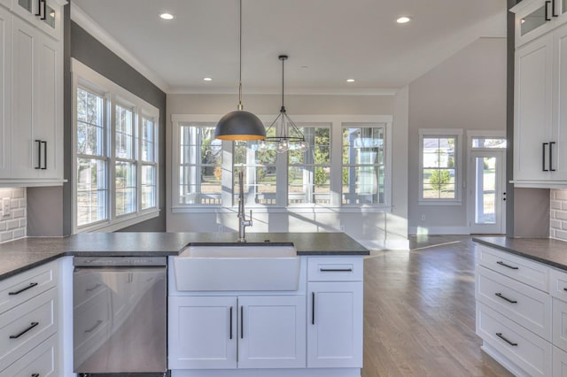 kitchen featuring decorative backsplash, white cabinetry, stainless steel dishwasher, and hanging light fixtures