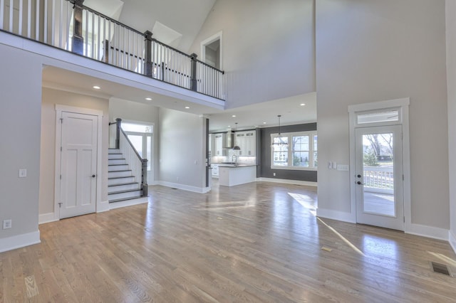 unfurnished living room featuring light hardwood / wood-style flooring and a towering ceiling