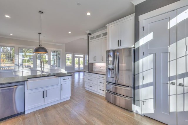 kitchen featuring tasteful backsplash, stainless steel appliances, sink, white cabinets, and hanging light fixtures