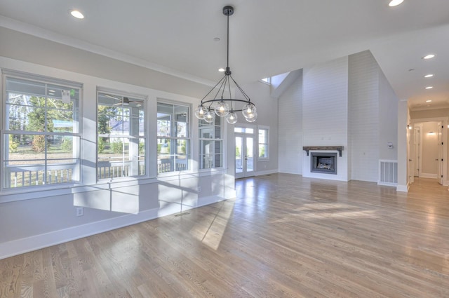 unfurnished living room featuring a large fireplace, light hardwood / wood-style floors, an inviting chandelier, and ornamental molding