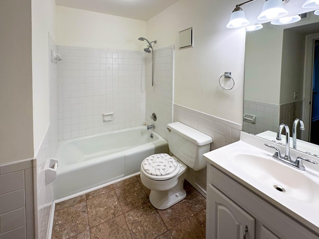 full bathroom featuring vanity, tiled shower / bath combo, tile walls, and toilet